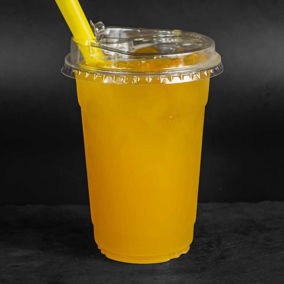 A Drizzle Cafe mango smoothie in a clear plastic cup with a yellow straw.