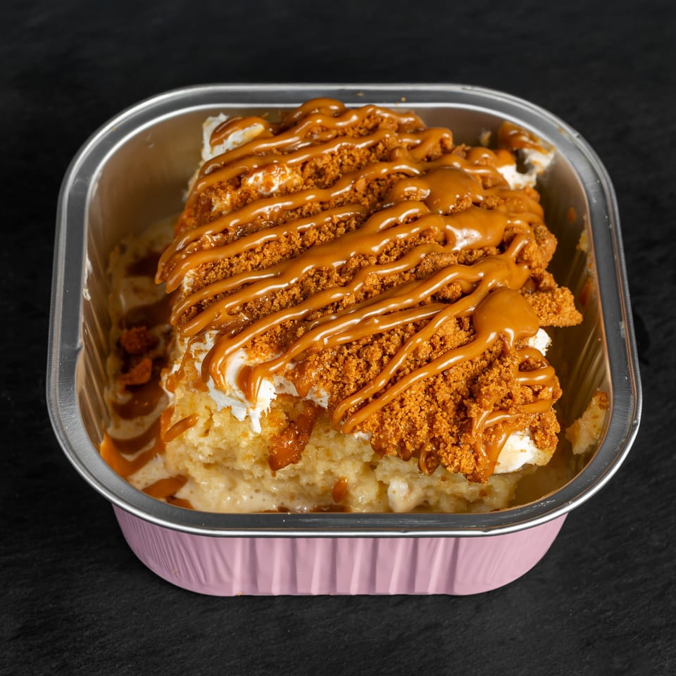 Drizzle Cafe's dessert in a pink foil container, topped with caramel drizzle and cookie crumbles.