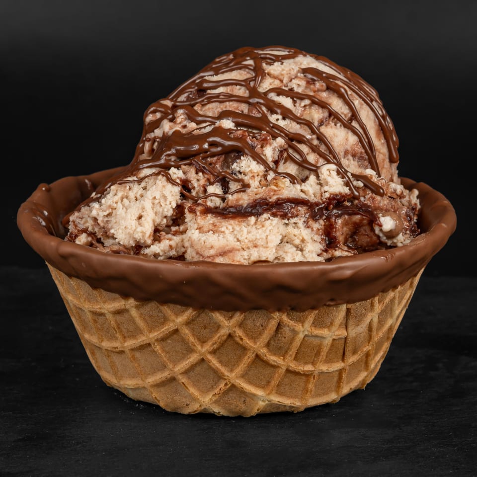 A scoop of Drizzle Cafe's chocolate chip ice cream drizzled with chocolate syrup in a waffle bowl.