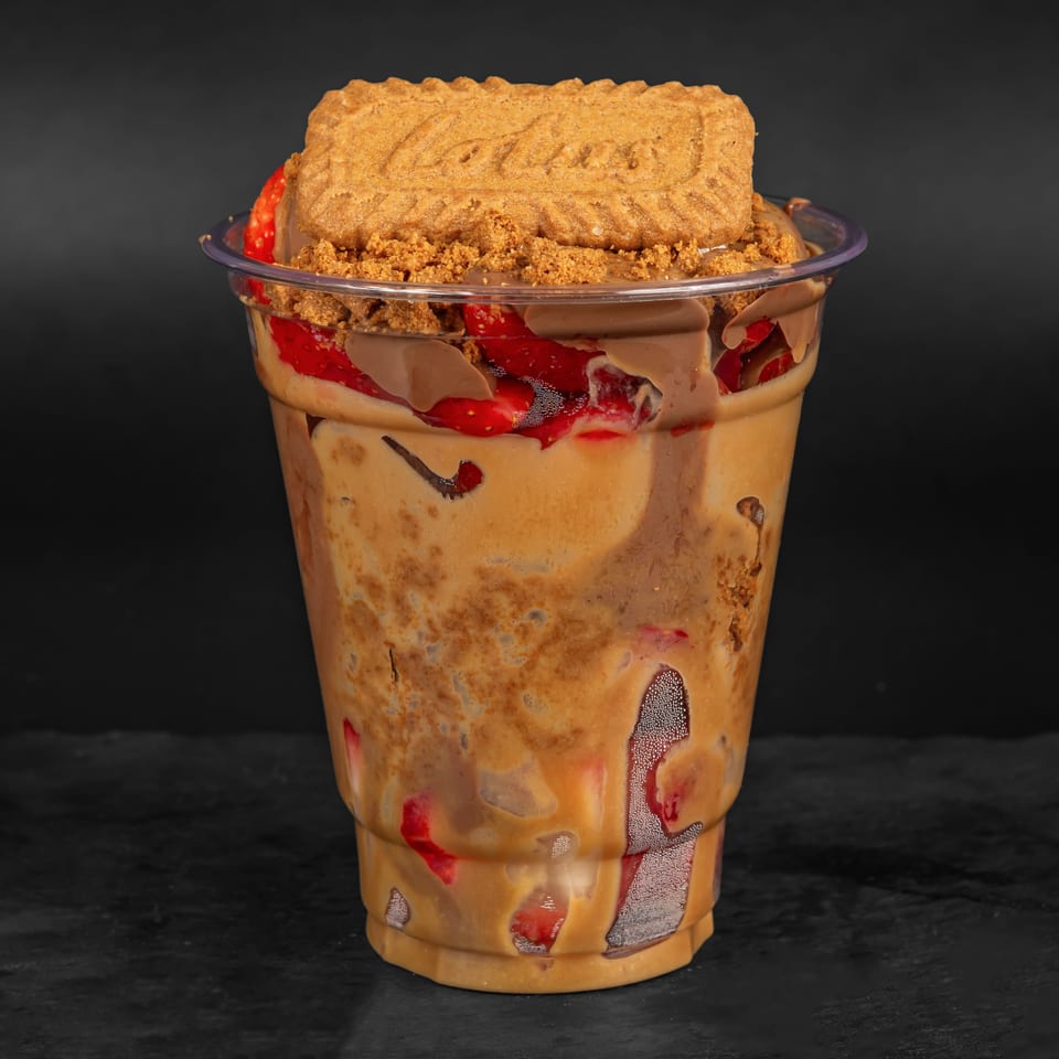 A Drizzle Cafe dessert cup with layers of caramel, chocolate, strawberries, and a Lotus Biscoff cookie.